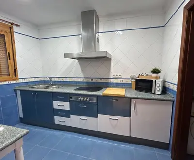 a blue and white kitchen with a stove and a microwave at Casa Mariquilla in Sanlúcar de Barrameda