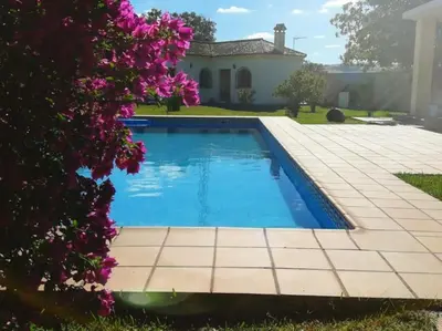 a swimming pool in front of a house with purple flowers at Casa 1 dormitorio con piscina privada y jardin in Arcos de la Frontera