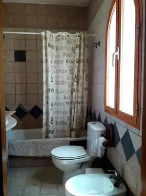 a bathroom with a toilet and a shower curtain at Casa 1 dormitorio con piscina privada y jardin in Arcos de la Frontera