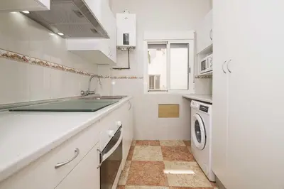 a white kitchen with a sink and a dishwasher at Velbar in Cádiz