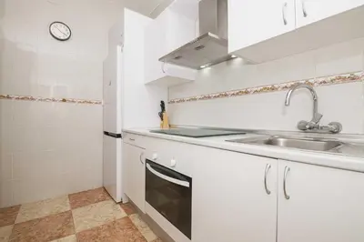 a kitchen with white cabinets and a sink at Velbar in Cádiz