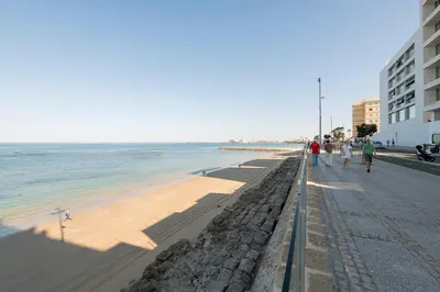 a beach with people walking on it next to the ocean at Velbar in Cádiz