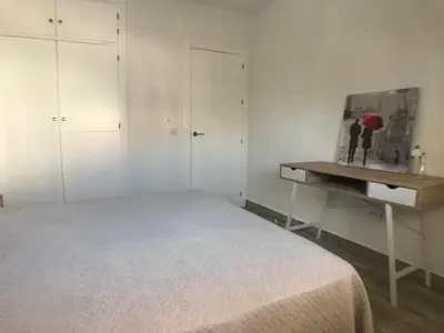 a white bedroom with a bed and a desk at Apartmento Apartaclub La Barrosa 223 in Chiclana de la Frontera