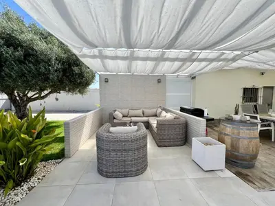 a patio with a couch and chairs under a canopy at Casa de la Luz in Chiclana de la Frontera