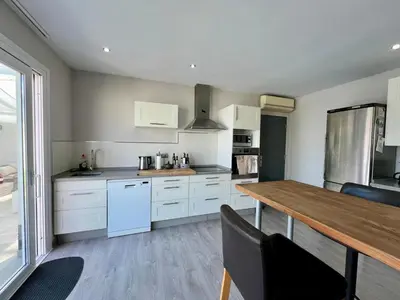 a kitchen with white cabinets and a wooden table at Casa de la Luz in Chiclana de la Frontera