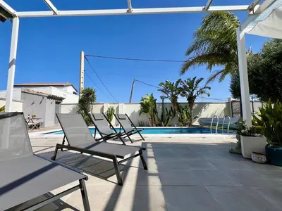 a group of chairs sitting next to a swimming pool at Casa de la Luz in Chiclana de la Frontera