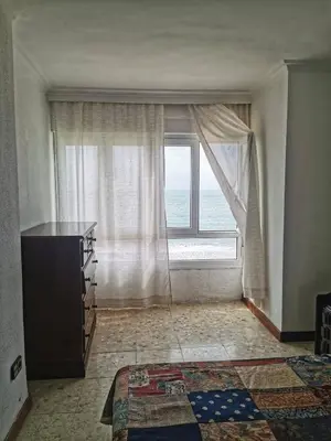 a room with a large window and a dresser in front thereof at Apartamento primera linea de playa in Cádiz