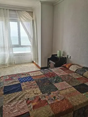 a bedroom with a quilt on a bed with a window at Apartamento primera linea de playa in Cádiz