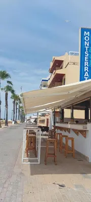 a group of tables and chairs on a street with a building at Montserrat Casa del Mar in Chipiona