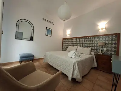 a bedroom with a bed and a chair and a mirror at Montserrat Casa del Mar in Chipiona