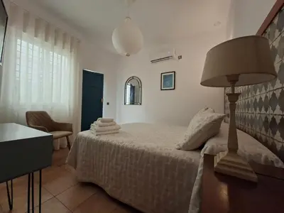 a bedroom with a bed with a lamp and a chair at Montserrat Casa del Mar in Chipiona