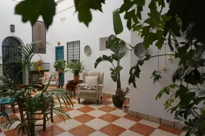 a courtyard with a chair and potted plants at Montserrat Casa del Mar in Chipiona