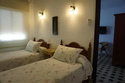 a hotel room with two beds and a table at Montserrat Casa del Mar in Chipiona
