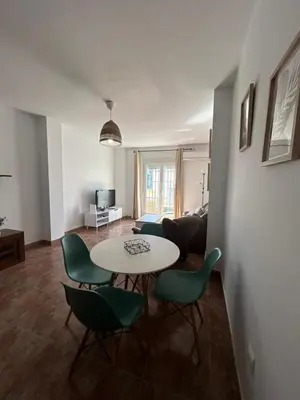 a living room with a table and green chairs at Barrameda 15 con parking in Sanlúcar de Barrameda