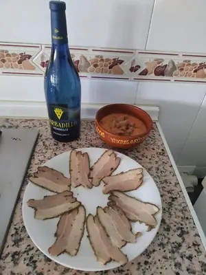 a plate of chicken on a counter with a bottle of wine at High Sanlúcar-Aparcamiento incluído in Sanlúcar de Barrameda