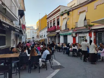 a group of people sitting at tables in a street at High Sanlúcar-Aparcamiento incluído in Sanlúcar de Barrameda