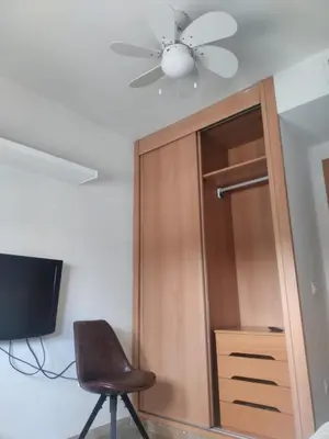 a ceiling fan and a chair next to a closet at High Sanlúcar-Aparcamiento incluído in Sanlúcar de Barrameda