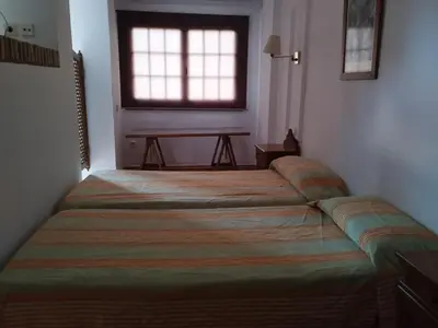 a bedroom with two beds and a window and a table at Apartamentos Jasmund - Estudio 0 in San Fernando