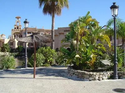 a resort with palm trees and an umbrella and a building at Apartamentos Jasmund - Estudio 0 in San Fernando