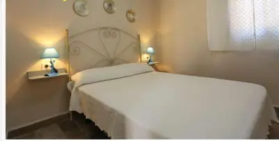 a bedroom with a large white bed with two lamps at Casa rural 1 in Conil de la Frontera