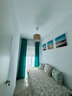 a bedroom with a bed and a window with blue curtains at Apartamentos Muñoz Fornell 2 in Chiclana de la Frontera