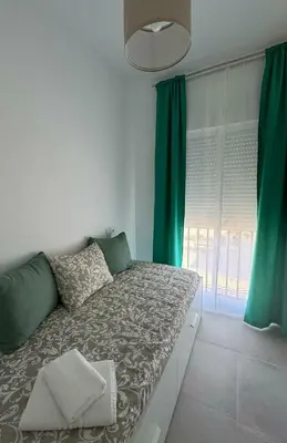 a bedroom with a large bed with green curtains at Apartamentos Muñoz Fornell 1 in Chiclana de la Frontera
