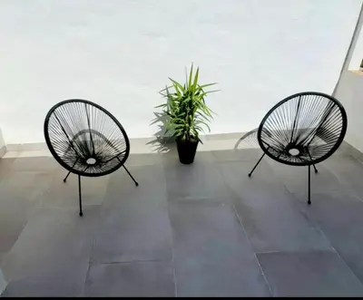 three black chairs in a room with a potted plant at Apartamentos Muñoz Fornell 1 in Chiclana de la Frontera