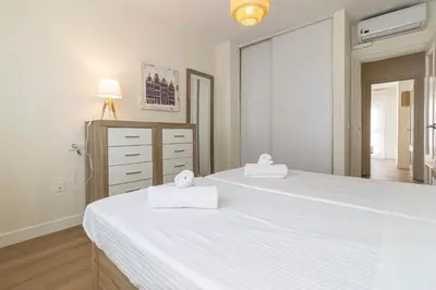 two white beds in a bedroom with a mirror at Allo Apartments Medina Duplex Parking 3 Habitaciones in Jerez de la Frontera