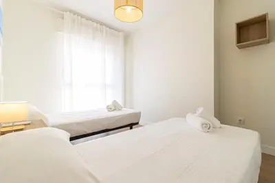two beds in a room with a window at Allo Apartments Medina Duplex Parking 3 Habitaciones in Jerez de la Frontera
