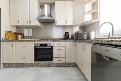 a kitchen with white cabinets and a black oven at Allo Apartments Medina Duplex Parking 3 Habitaciones in Jerez de la Frontera