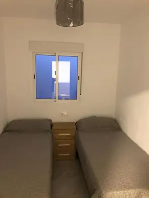 two beds in a small room with a window at Vivienda con piscina Jacuzzi in Chiclana de la Frontera