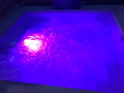 a pool with a purple light in the water at Vivienda con piscina Jacuzzi in Chiclana de la Frontera