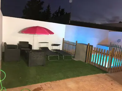 a patio with a table and chairs and an umbrella at Vivienda con piscina Jacuzzi in Chiclana de la Frontera