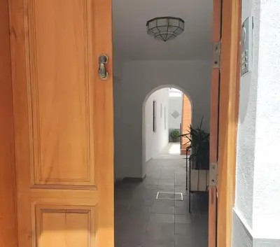 a hallway with a wooden door and an archway at Casa Bakio in Sanlúcar de Barrameda