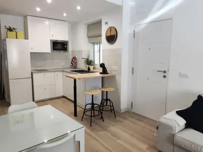 a kitchen and living room with a table and chairs at Casa Bakio in Sanlúcar de Barrameda