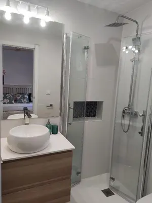 a white bathroom with a sink and a shower at Casa Laida in Sanlúcar de Barrameda