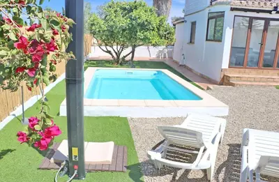 a swimming pool in a yard with two chairs and a house at Casa Abuelo Miguel in Conil de la Frontera