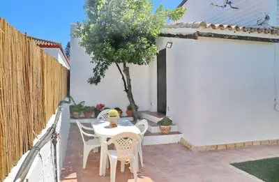 a table and chairs on a patio with a tree at Casa Abuelo Miguel in Conil de la Frontera