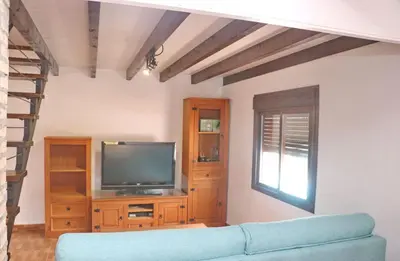 a living room with a blue couch and a television at Casa Abuelo Miguel in Conil de la Frontera