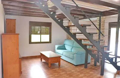 a living room with a blue couch and a spiral staircase at Casa Abuelo Miguel in Conil de la Frontera