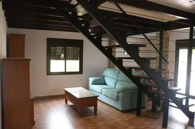 a living room with a blue couch and a spiral staircase at Casa Abuelo Miguel in Conil de la Frontera