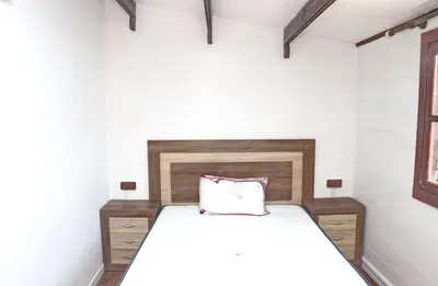 a small bedroom with a bed with a wooden headboard at Casa Abuelo Miguel in Conil de la Frontera