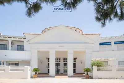 a white building with a street sign on top at Apartamento los jardines in Sanlúcar de Barrameda