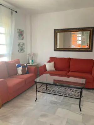 a living room with a red couch and a table at ÁTICO Jardines de la salinera de VALDELAGRANA in El Puerto de Santa María