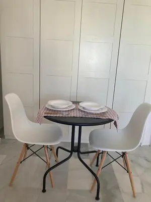 two white chairs and a table with two plates on it at ÁTICO Jardines de la salinera de VALDELAGRANA in El Puerto de Santa María