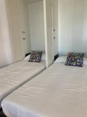 two beds in a room with white walls at ÁTICO Jardines de la salinera de VALDELAGRANA in El Puerto de Santa María