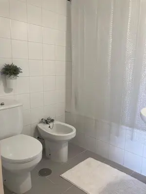 a white bathroom with a toilet and a sink at ÁTICO Jardines de la salinera de VALDELAGRANA in El Puerto de Santa María