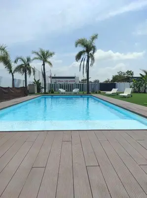 a large swimming pool with a wooden floor and palm trees at Finca Rural Marmito in Sanlúcar de Barrameda