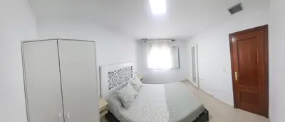 a white bedroom with a bed and a window at Casa Andrea in Puerto Real