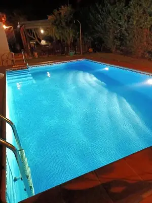 a large blue swimming pool at night at Chalet Roche a 300 metros de la playa in Roche